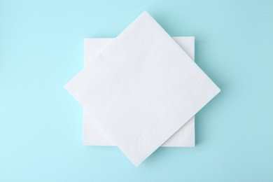 Photo of Stack of disposable paper handkerchiefs on light blue background, top view