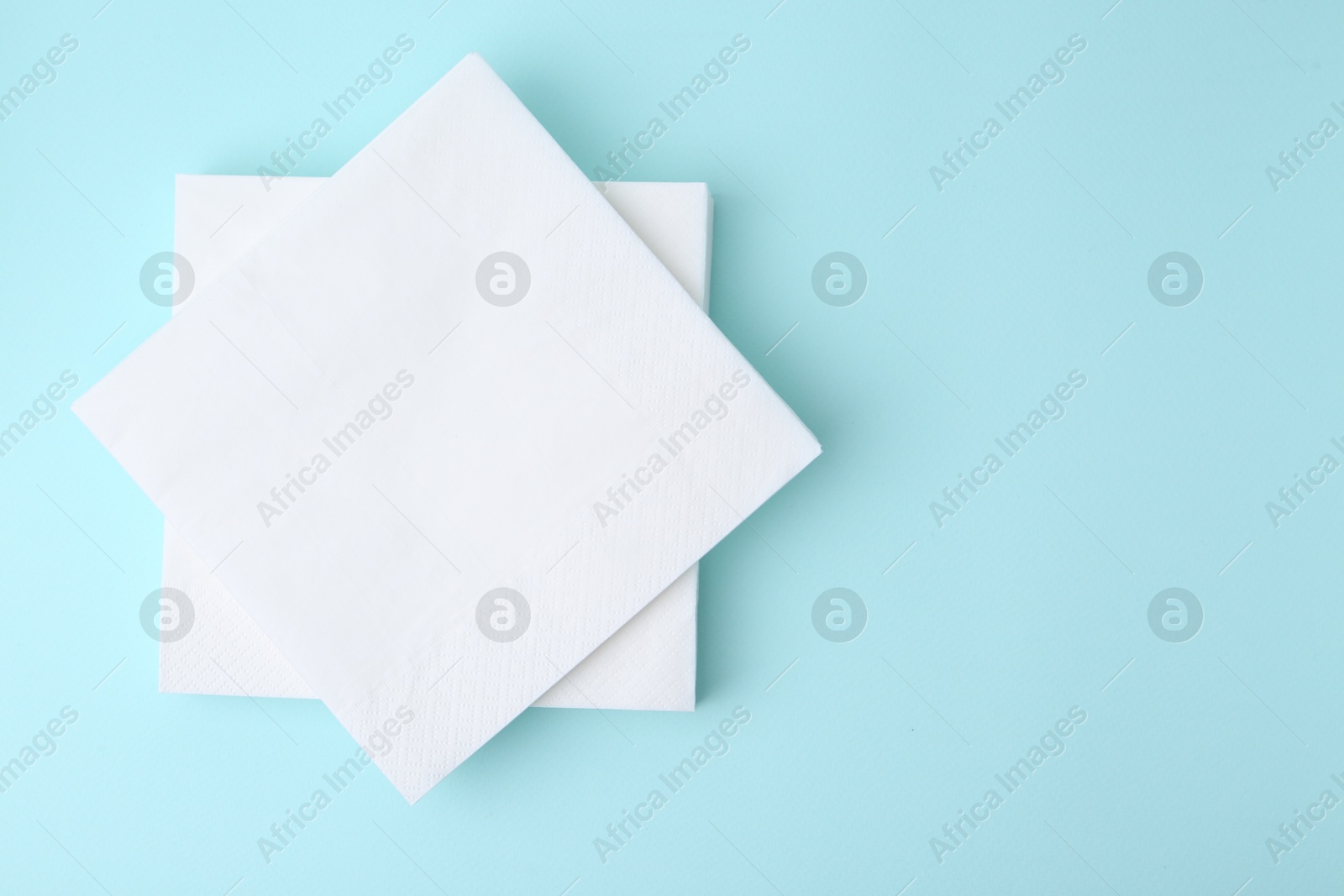 Stack of disposable paper handkerchiefs on light blue background, top view. Space for text Photo of Stack of disposable paper handkerchiefs on light blue background, top view. Space for text
