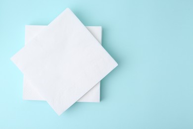 Photo of Stack of disposable paper handkerchiefs on light blue background, top view. Space for text