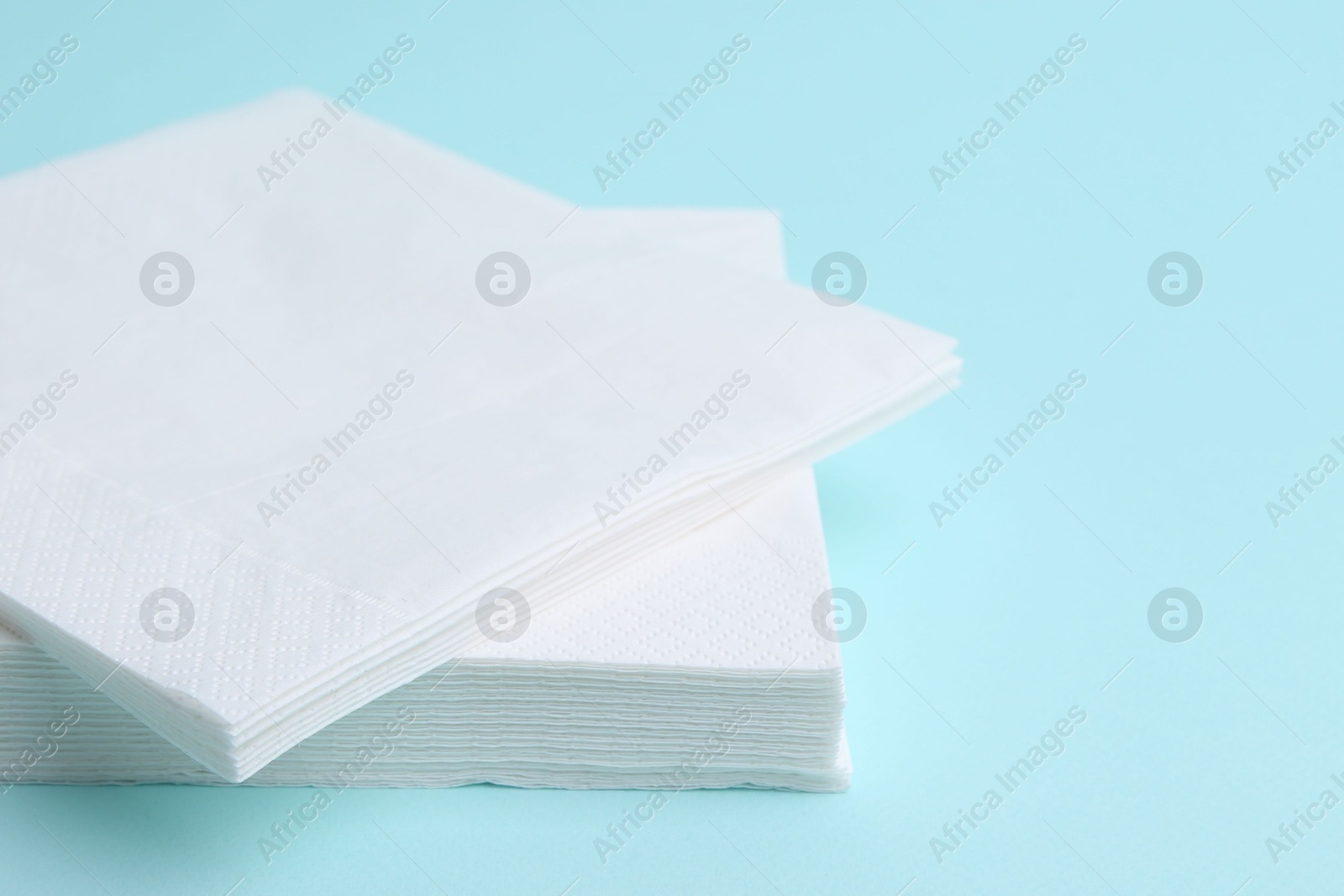 Stack of disposable paper handkerchiefs on light blue background, closeup Photo of Stack of disposable paper handkerchiefs on light blue background, closeup