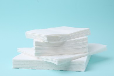 Photo of Stack of disposable paper handkerchiefs on light blue background, closeup