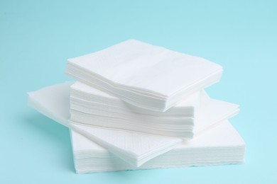 Photo of Stack of disposable paper handkerchiefs on light blue background, closeup