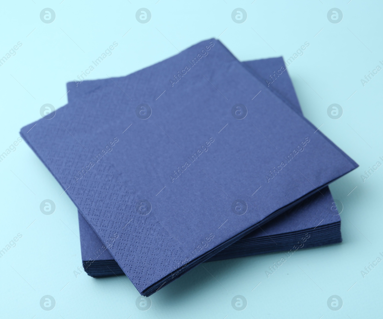 Stack of disposable paper handkerchiefs on light blue background, closeup Photo of Stack of disposable paper handkerchiefs on light blue background, closeup
