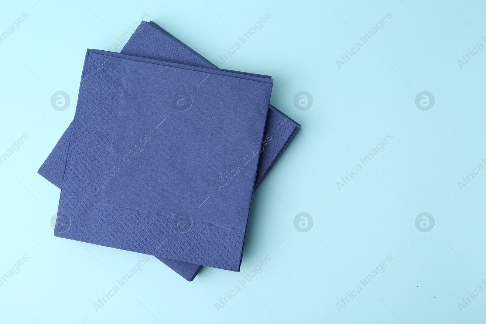 Stack of disposable paper handkerchiefs on light blue background, top view. Space for text Photo of Stack of disposable paper handkerchiefs on light blue background, top view. Space for text