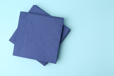 Photo of Stack of disposable paper handkerchiefs on light blue background, top view. Space for text