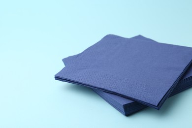 Photo of Stack of disposable paper handkerchiefs on light blue background, closeup. Space for text