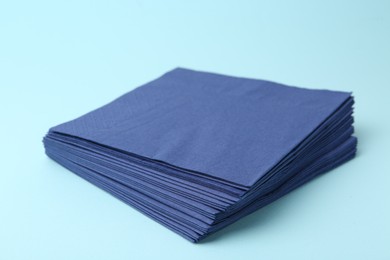 Photo of Stack of disposable paper handkerchiefs on light blue background, closeup