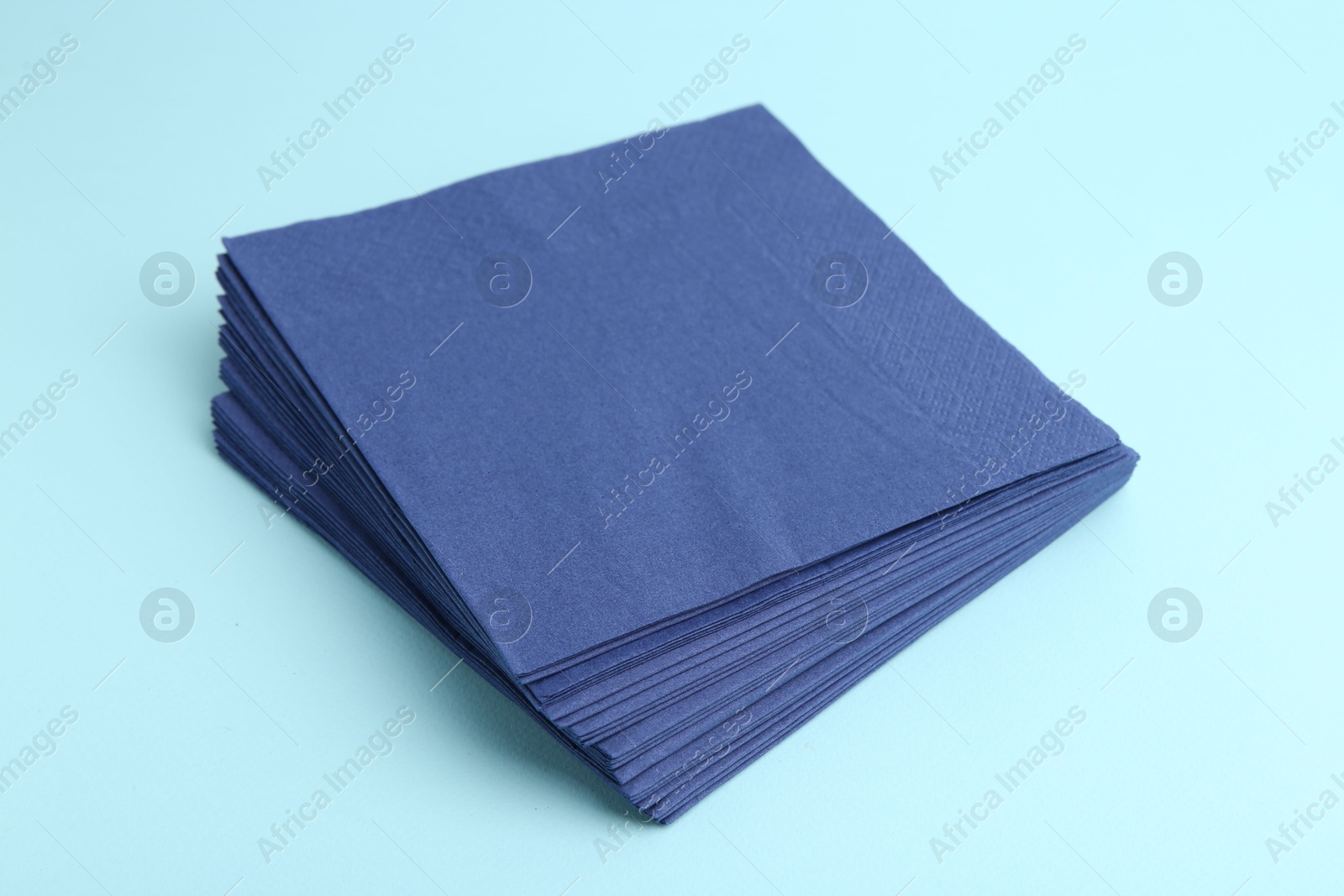 Stack of disposable paper handkerchiefs on light blue background, closeup Photo of Stack of disposable paper handkerchiefs on light blue background, closeup