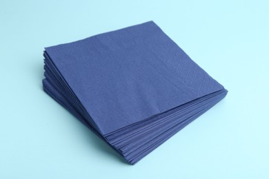 Photo of Stack of disposable paper handkerchiefs on light blue background, closeup