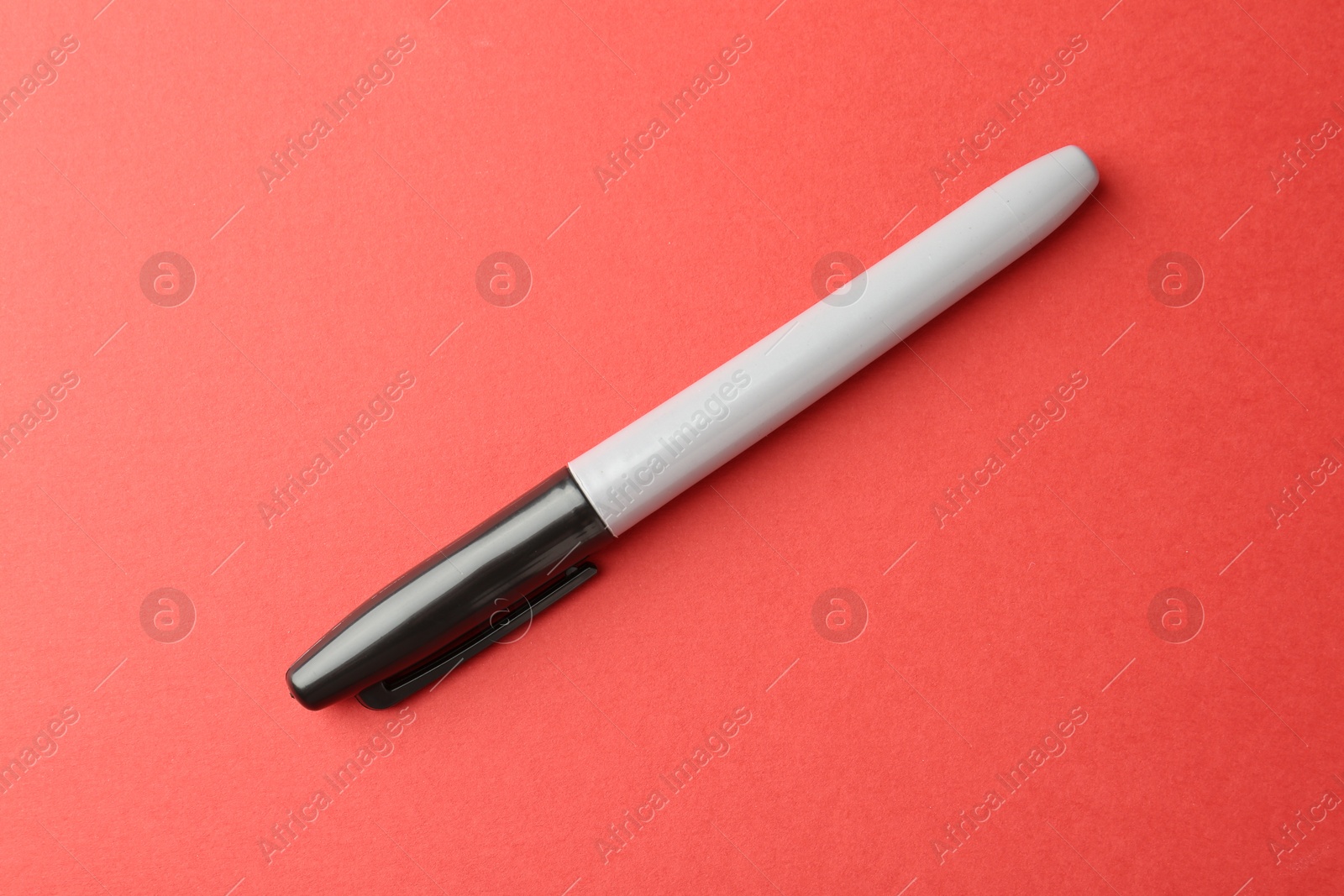 One black marker on red background, top view Photo of One black marker on red background, top view