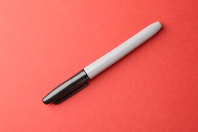 Photo of One black marker on red background, top view