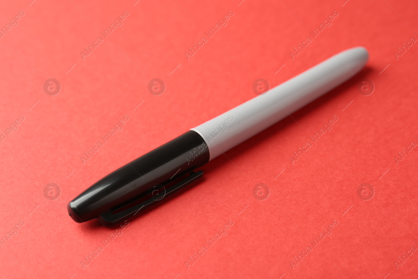 One black marker on red background, closeup Photo of One black marker on red background, closeup