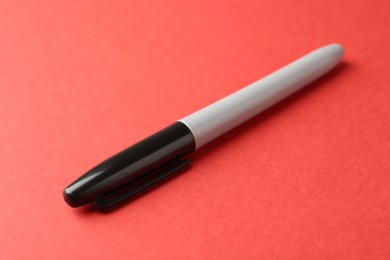 Photo of One black marker on red background, closeup
