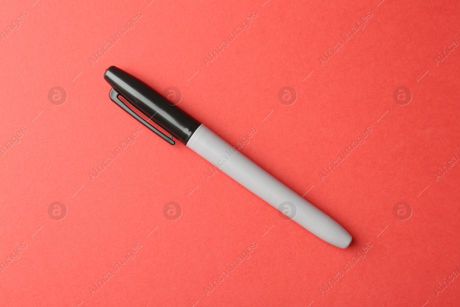 One black marker on red background, top view Photo of One black marker on red background, top view