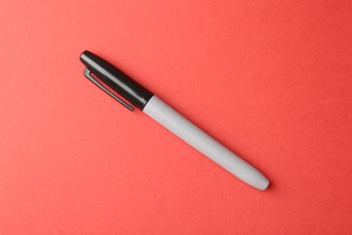 Photo of One black marker on red background, top view