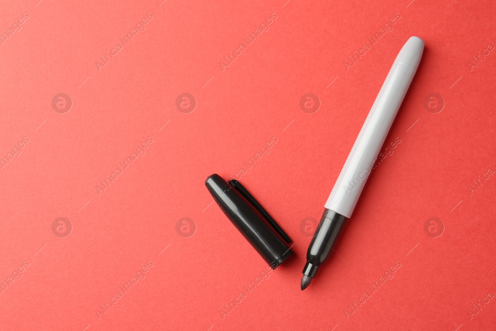 One black marker on red background, top view. Space for text Photo of One black marker on red background, top view. Space for text