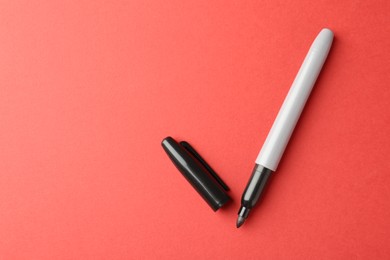 Photo of One black marker on red background, top view. Space for text