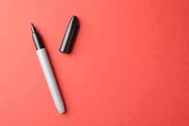 Photo of One black marker on red background, top view. Space for text