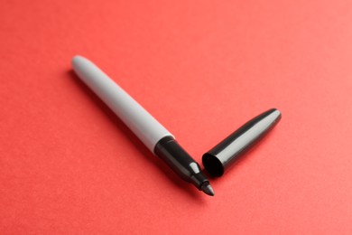 Photo of One black marker on red background, closeup