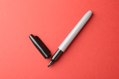 Photo of One black marker on red background, top view
