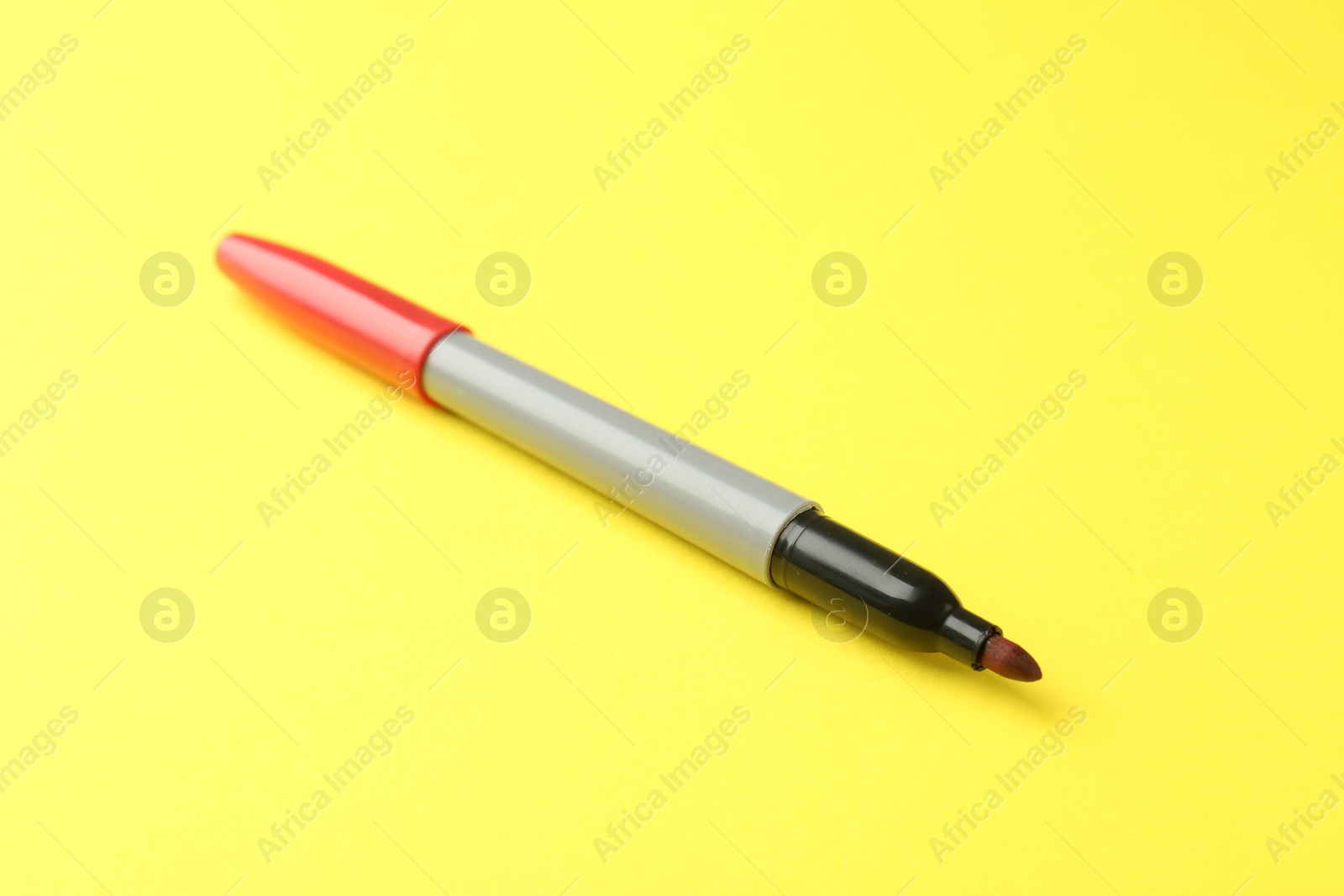 One red marker with cap on yellow background Photo of One red marker with cap on yellow background