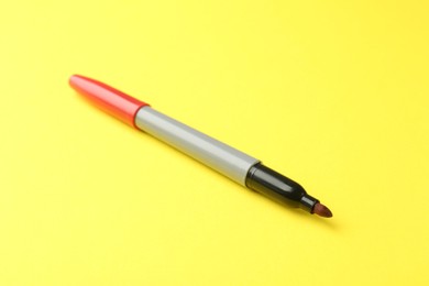 Photo of One red marker with cap on yellow background