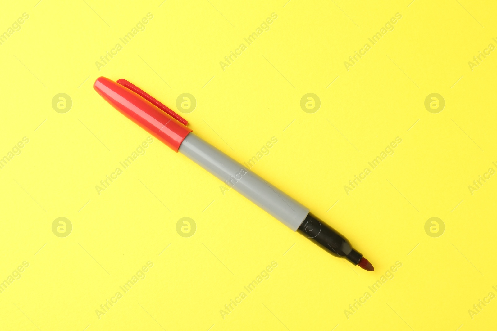 One red marker on yellow background, top view Photo of One red marker on yellow background, top view