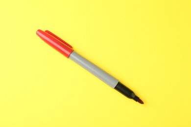 Photo of One red marker on yellow background, top view