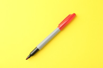 Photo of One red marker on yellow background, top view