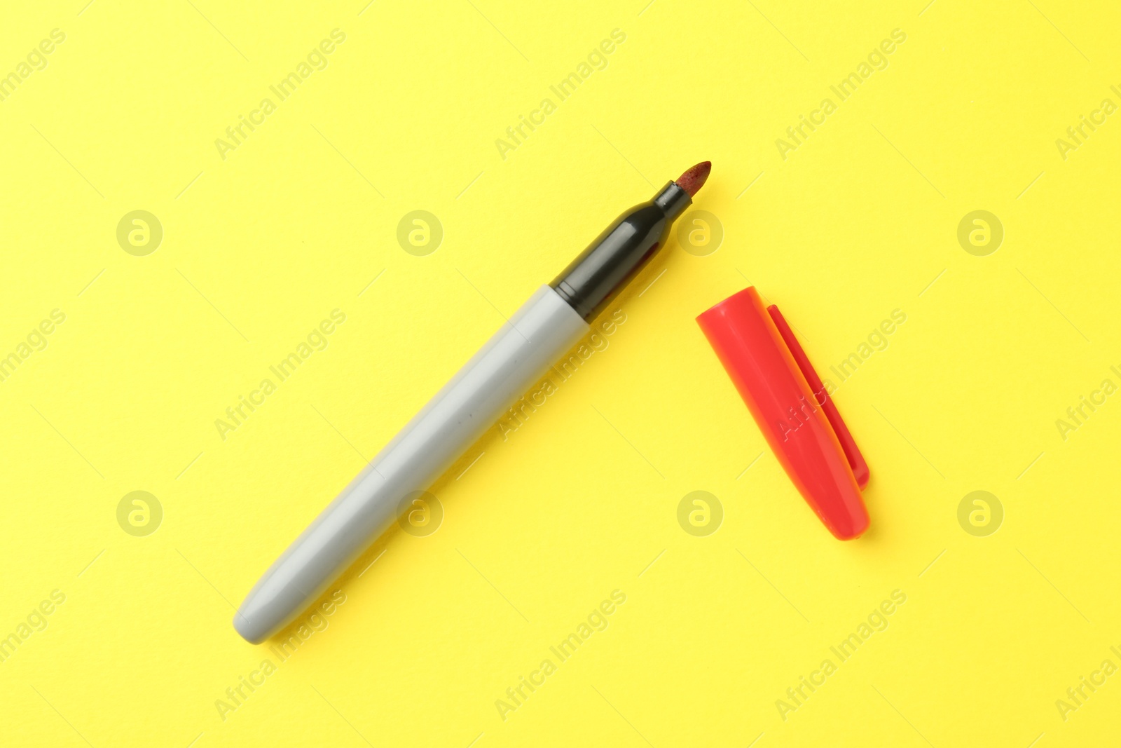 One red marker on yellow background, top view Photo of One red marker on yellow background, top view