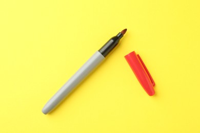 Photo of One red marker on yellow background, top view
