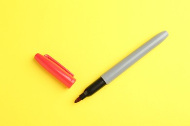 Photo of One red marker on yellow background, top view