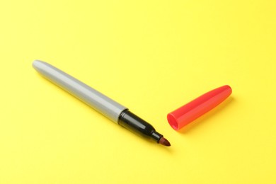 Photo of One red marker with cap on yellow background. Space for text