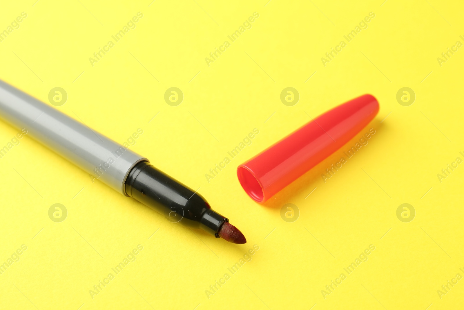 One red marker on yellow background, closeup Photo of One red marker on yellow background, closeup