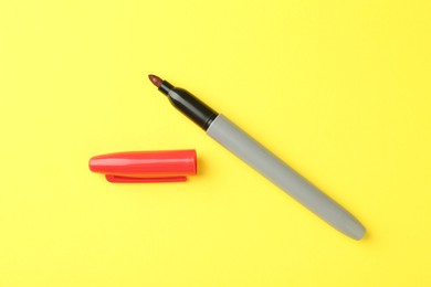Photo of One red marker on yellow background, top view