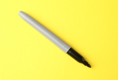 Photo of One black marker on yellow background, top view. Space for text