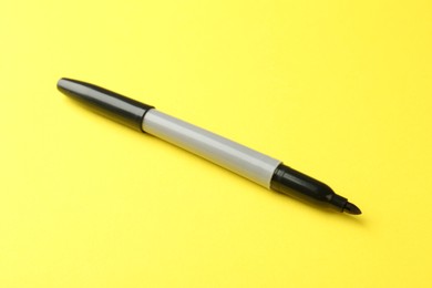 Photo of One black marker on yellow background, closeup