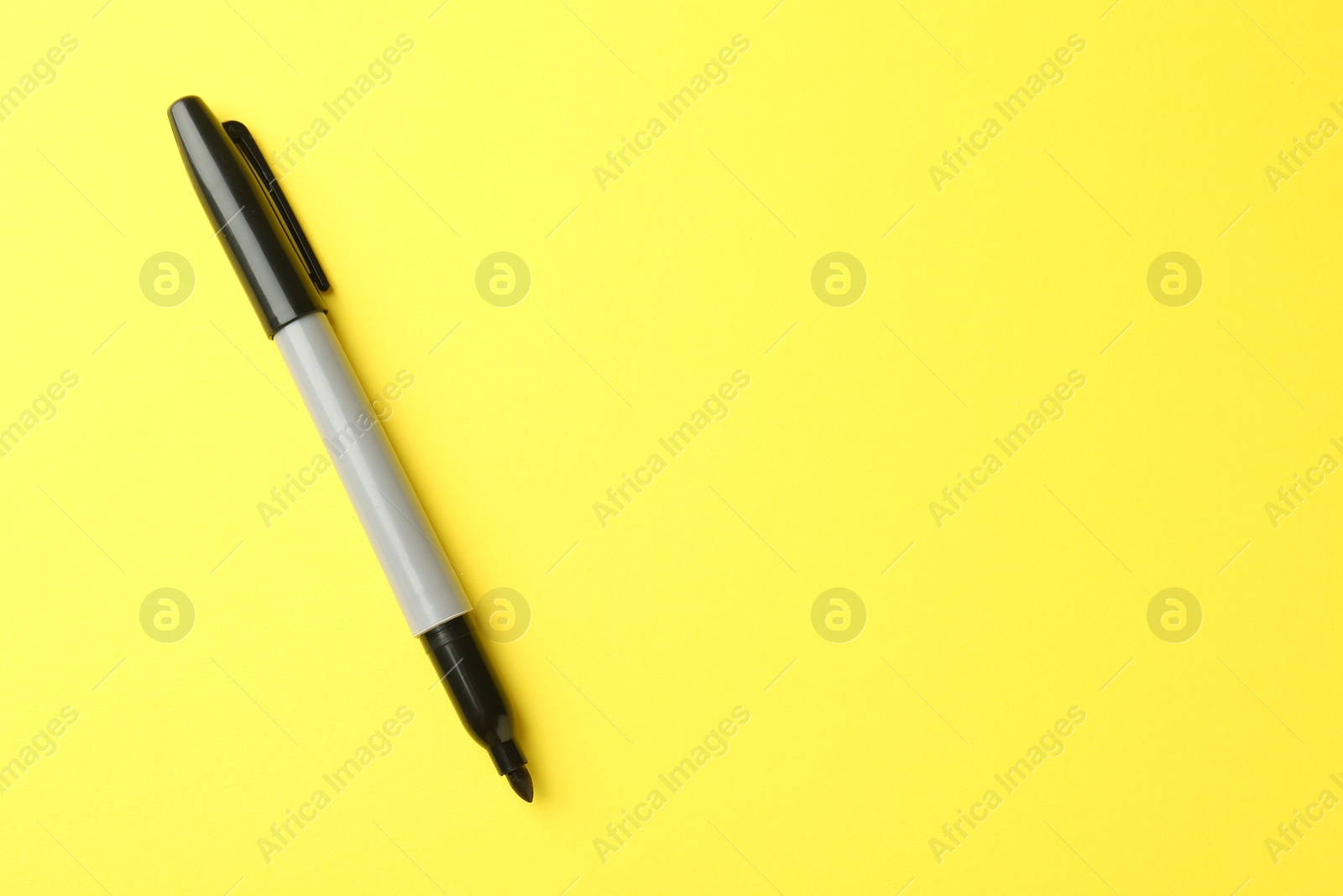 One black marker on yellow background, top view. Space for text Photo of One black marker on yellow background, top view. Space for text