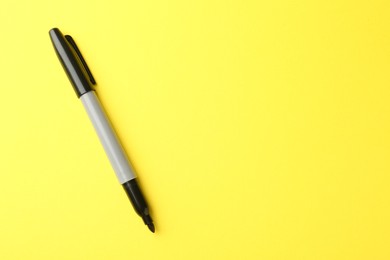 Photo of One black marker on yellow background, top view. Space for text