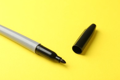 Photo of One black marker on yellow background, closeup. Space for text