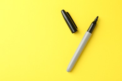 Photo of One black marker on yellow background, top view. Space for text