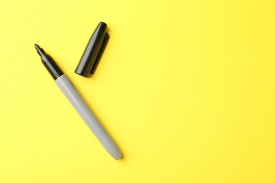Photo of One black marker on yellow background, top view. Space for text