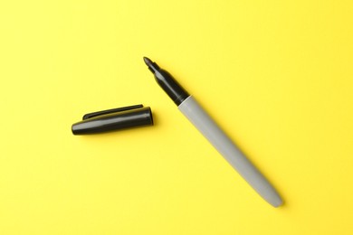 Photo of One black marker on yellow background, top view