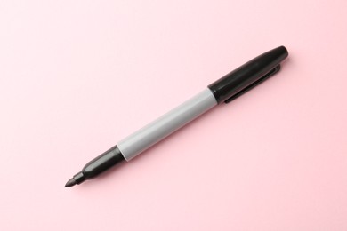 Photo of One black marker on light pink background, top view