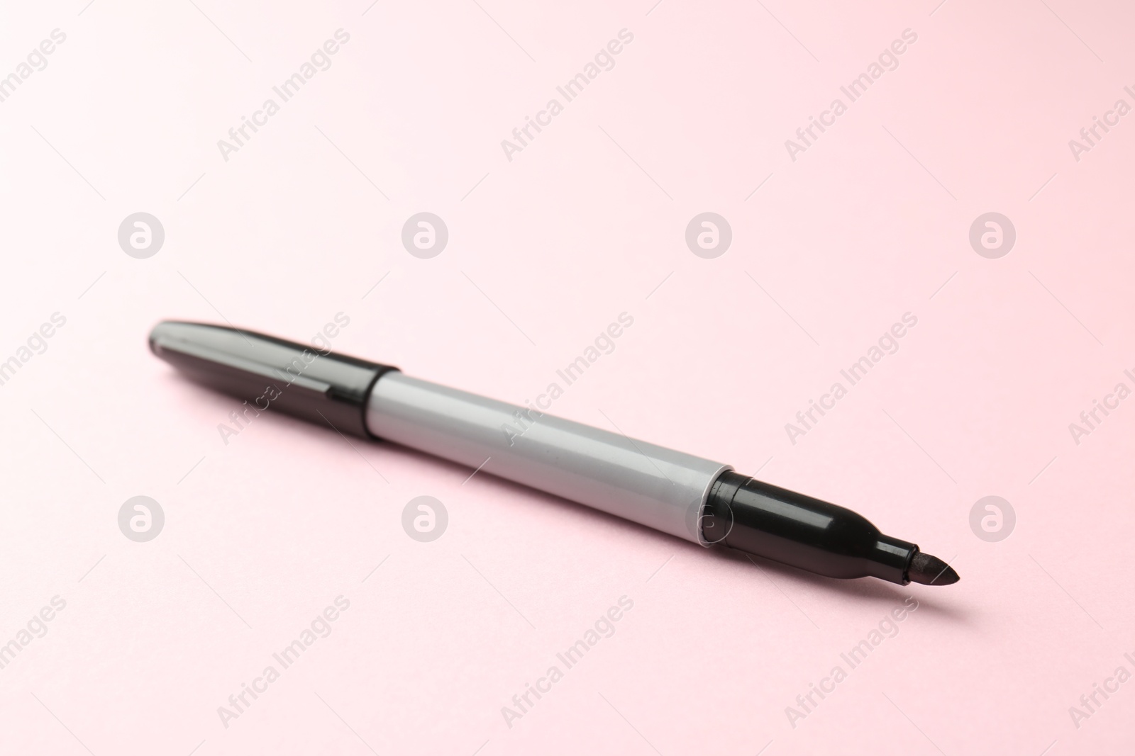 One black marker on light pink background, closeup. Space for text Photo of One black marker on light pink background, closeup. Space for text