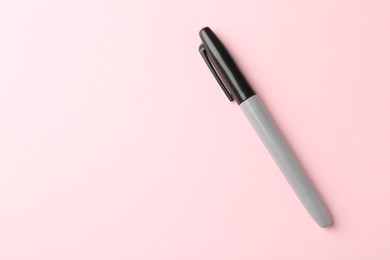 Photo of One black marker on light pink background, top view. Space for text