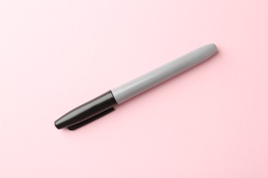 Photo of One black marker on light pink background, top view