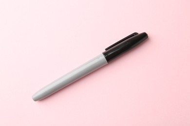 Photo of One black marker on light pink background, top view