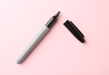 Photo of One black marker on light pink background, top view
