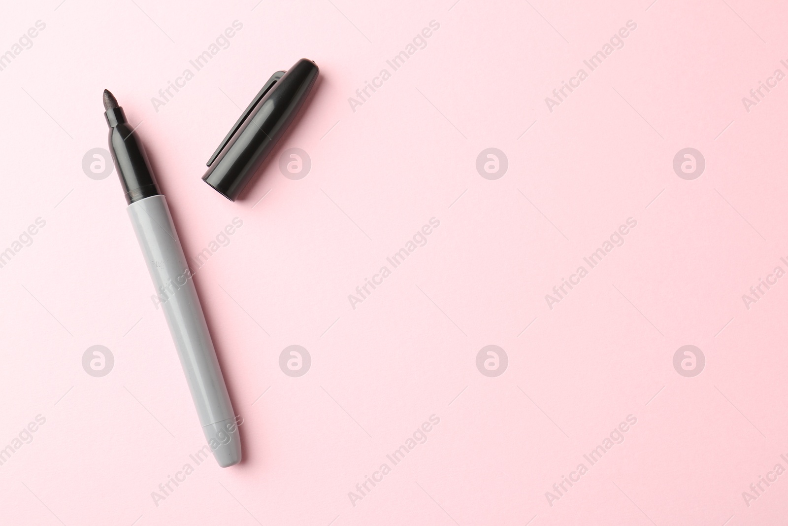 Photo of One black marker on light pink background, top view. Space for text